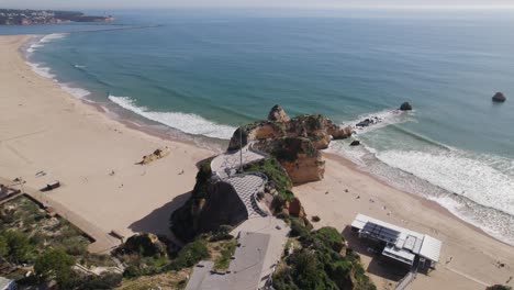 Toma-En-órbita-Sobre-El-Mirador-De-Tres-Castillos-En-La-Playa-De-Rocha-En-Un-Día-Soleado,-Portimão