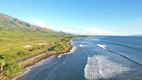 Aerial-view-of-coast-and-waves-with-road-and-traffic-on-the-left-side