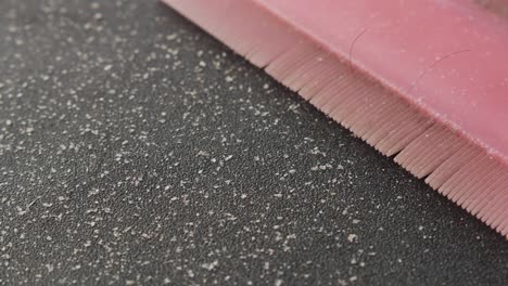 close-up of a pink hairbrush and a dusty surface