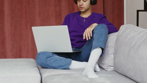 joven usando una computadora portátil en el sofá