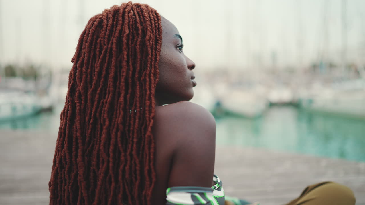 Woman with dreadlocks sitting on a dock