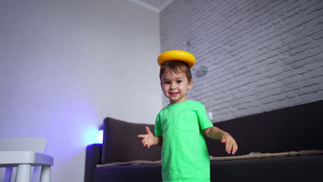 smiling kid holding a piece of pyramid on his head. adorable baby drops the toy and then turns it as a steering wheel. low angle view.