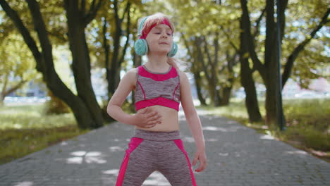 Sport-runner-child-girl-training-exercise-listening-music-on-headphones-dancing-to-camera-having-fun