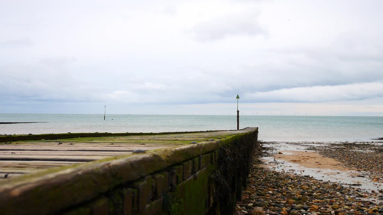 잔잔한 흐린 바다로 이어지는 풍화 나무 판자 산책로 천천히 떠오르는 샷