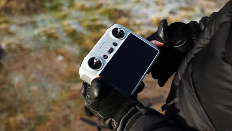 person with leather gloves push and hold remote control button, turn on device