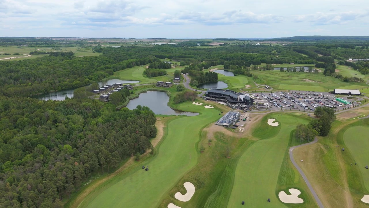Luftaufnahmen zeigen die üppigen Fairways, makellosen Sandbunker, Wasserhindernisse und den umliegenden grünen Wald des TPC Toronto Osprey Valley Golf Course bei hellem Tageslicht in einer weitläufigen Vogelperspektive.