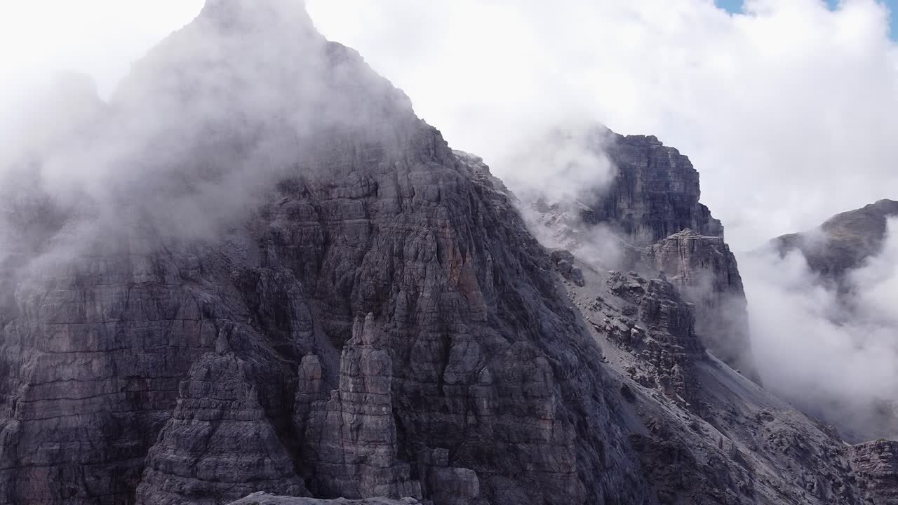 aerial de cordilleras alpinas rocosas empinadas, nubes de niebla alrededor del pico, paisaje épico paisaje no tripulado