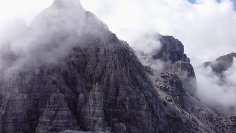 Antena-De-Escarpadas-Cadenas-Montañosas-Alpinas-Rocosas,-Nubes-Nubladas-Alrededor-Del-Pico,-Paisaje-épico-De-Drones