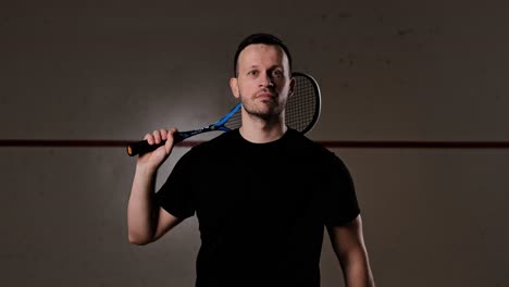 athlete confidently looks at camera, tosses squash ball in dramatic slow motion