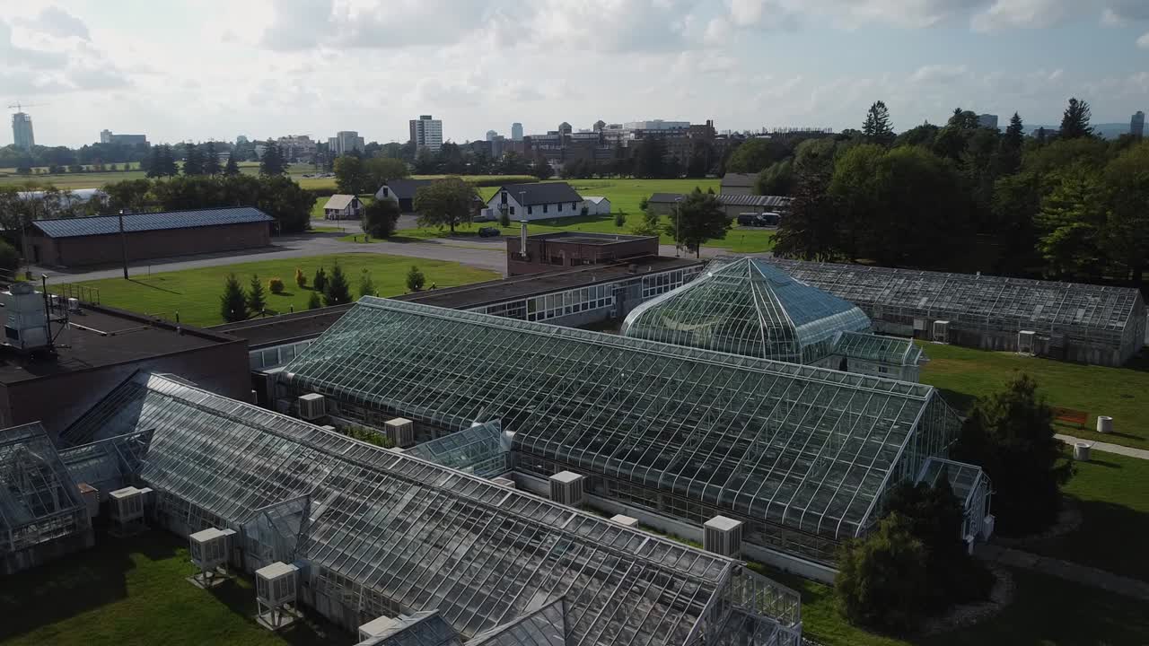 Sun reflecting off of large glass greenhouse with city in background