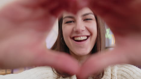 Eine-Glückliche-Junge-Frau-Macht-Ein-Symbol-Der-Liebe-Und-Zeigt-Ein-Herzzeichen-In-Die-Kamera,-Um-Romantische-Gefühle-Auszudrücken