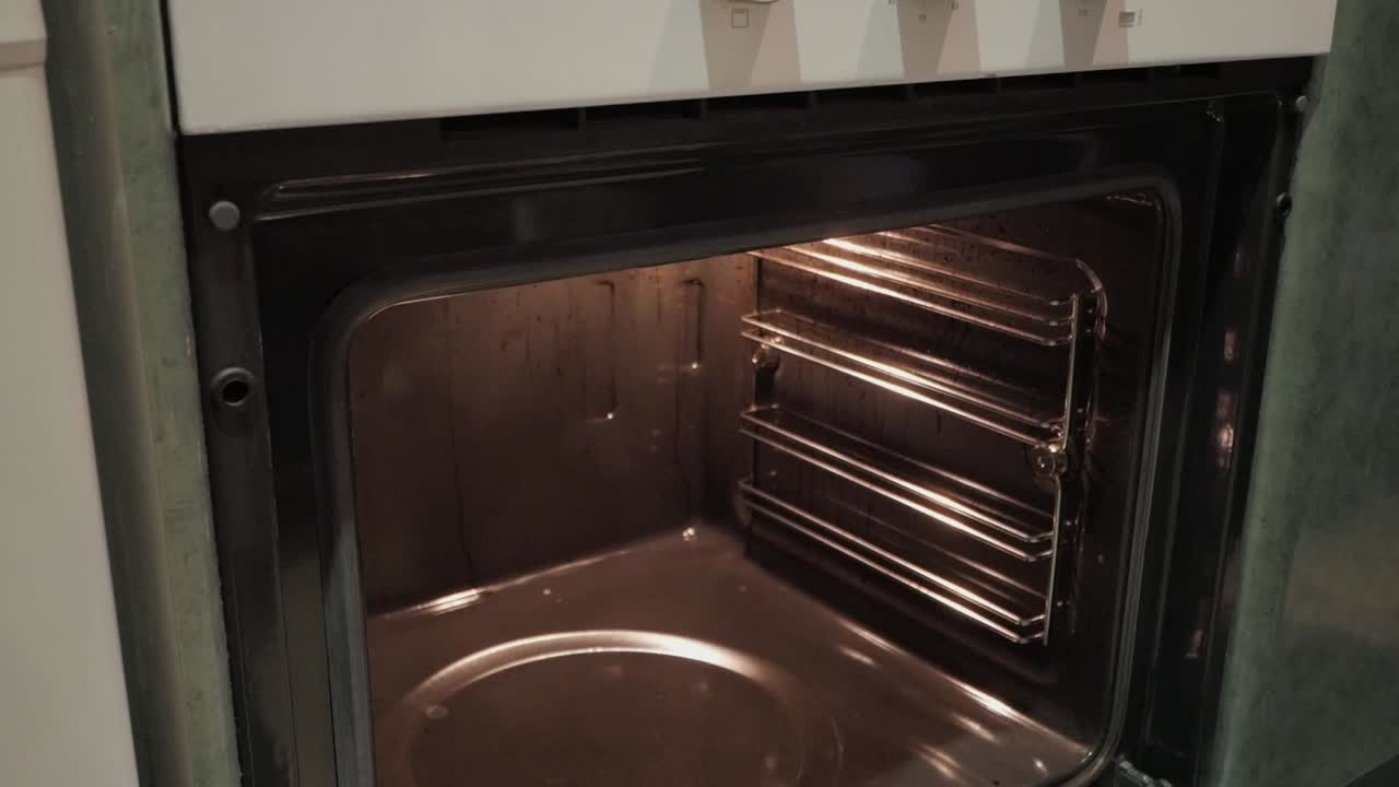 A rack of ribs being taken out of the oven, with a pair of oven mitts grabbing the tray