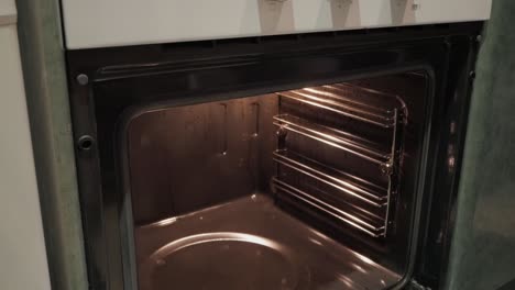 a rack of ribs being taken out of the oven, with a pair of oven mitts grabbing the tray