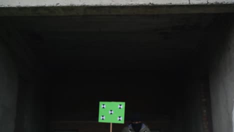 a man dressed in a black mask on his face holds a poster in his hands, comes out of the tunnel and waves them. copy space tracking points. blank green screen board.