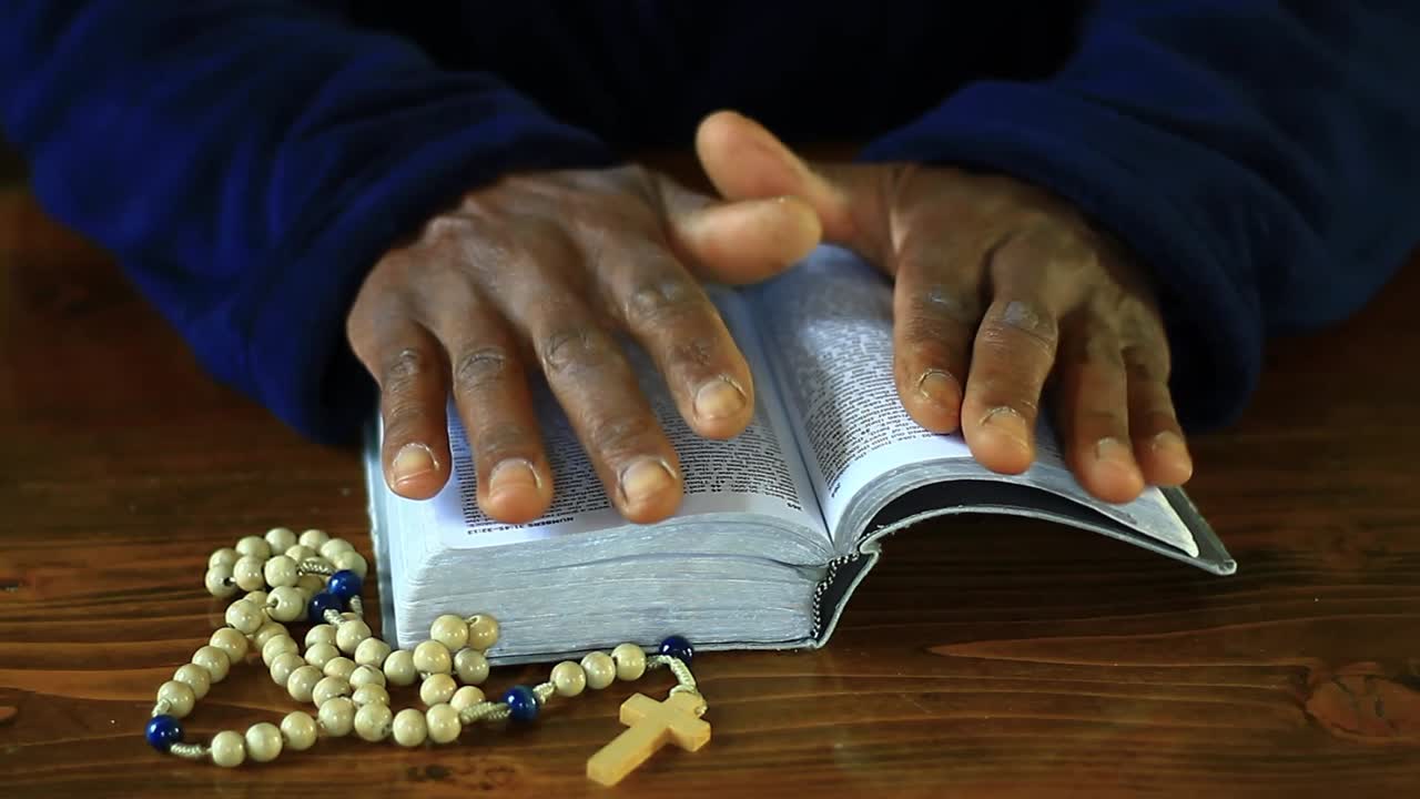 Prier Dieu les mains jointes sur une bible avec des personnes et un fond blanc, vidéo de stock