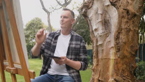 man painting on canvas in the garden 4k