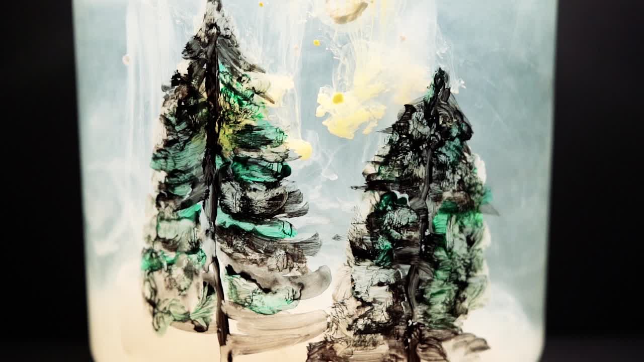 Yellow paint floating in water tank with pine trees drawing inside. Stable shot with the Sony a7iii.