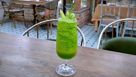 healthy kale smoothie served on a wooden restaurant table, revealed by an orbital panning shot