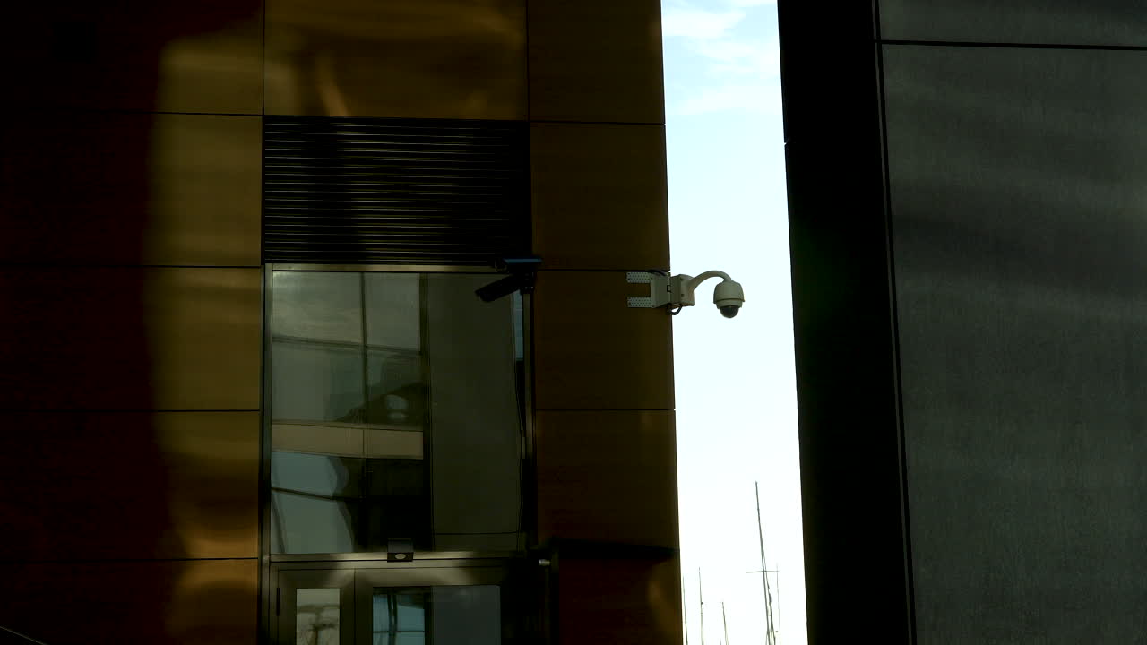 камера безопасности на здании с золотыми отражающими окнами и тенью