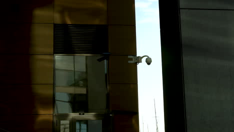 cámara de seguridad en un edificio con ventanas reflectantes doradas y una sombra