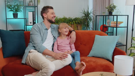 Young-man-father-having-trustworthy-conversation,-talking-with-daughter-child-kid-at-home-sofa