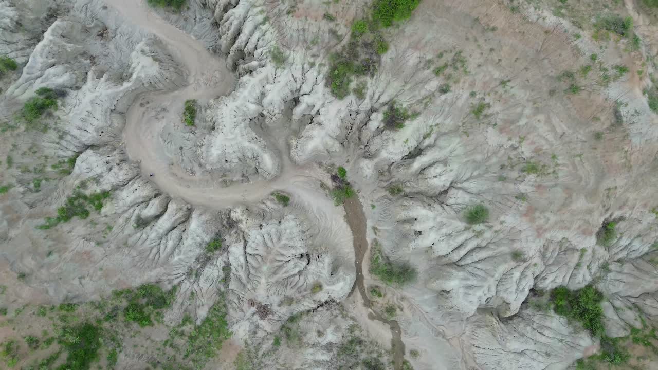 Sebuah drone melayang di atas gurun abu-abu Tatacoa, menampakkan bukit-bukit perak lembut dan ngarai yang tenang. Cahaya lembut membentuk lanskap tenang yang menyerupai bulan di jantung Kolombia.