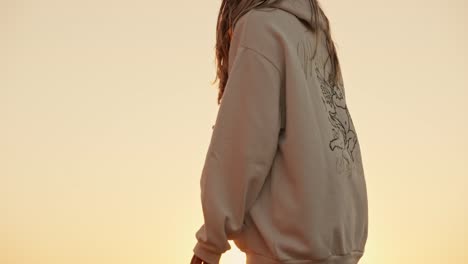 Teenager-in-shorts-and-sweatshirt-looking-sun-setting-over-sea-from-the-rocks