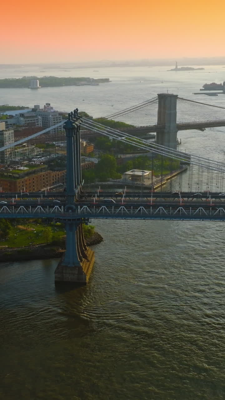 Cars moving by the Manhattan Bridge. Stunning view of the city and endless river against fantastic pink and orange sky. Vertical video