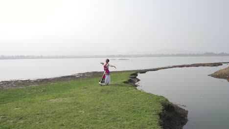 una bailarina de bharatnatyam que muestra una pose clásica de bharatnatyam en la naturaleza del lago vadatalav, pavagadh