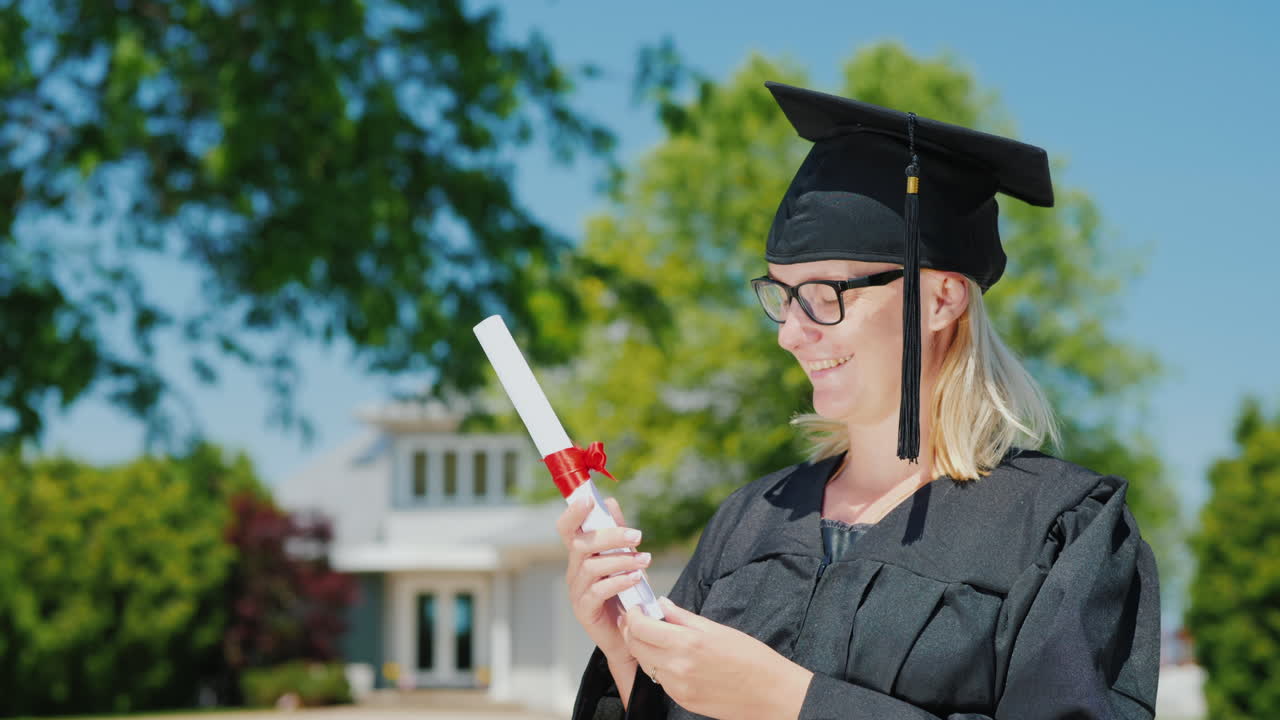 retrato de una mujer en un manto y gorra de graduación sosteniendo un diploma en la mano contra el centrico