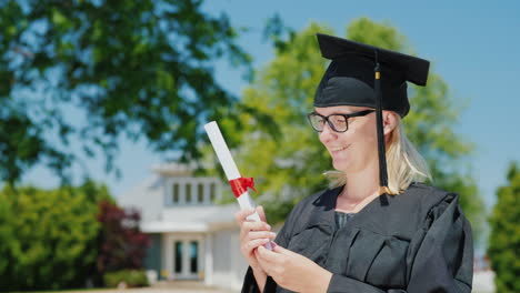 retrato de una mujer en un manto y gorra de graduación sosteniendo un diploma en la mano contra el centrico