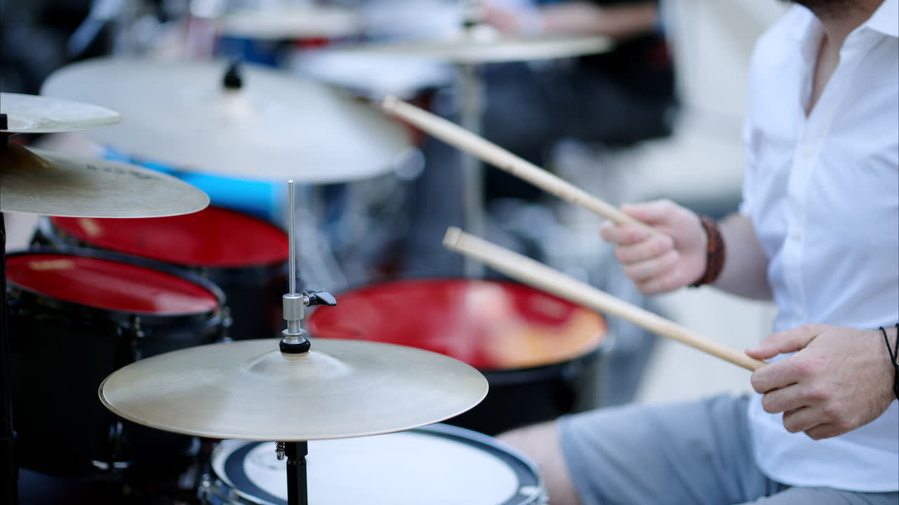 Close up of man playing red drums outside