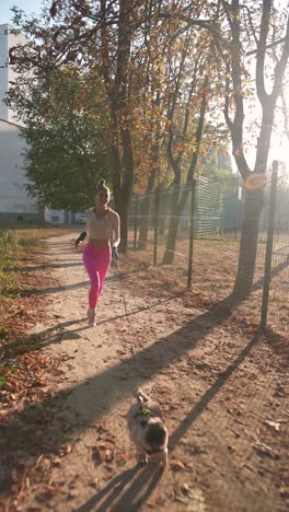 woman jogging with her dog in a park during autumn