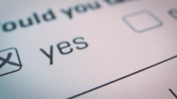 Slow-motion close-up over the checked YES box on official form white document, voting, decisions, choices of yes or no checkbox