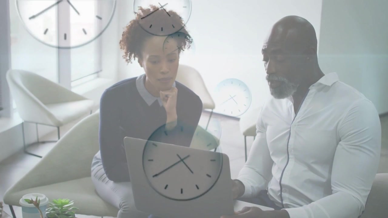 Colleagues placing laptop on woman's lap, reviewing while clocks overlay marking business deadline