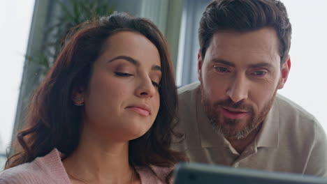 talking newlyweds looking tablet screen at apartment closeup. lovers discussing