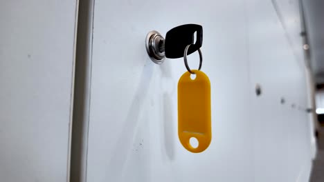 Close-up-image-showing-a-locker-key-with-a-yellow-key-tag-inserted-into-a-cupboard-lock,-symbolizing-security-and-access