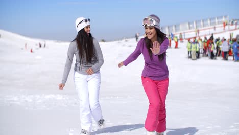 Dos-Mujeres-Jóvenes-Atractivas-Caminando-En-La-Nieve-Fresca