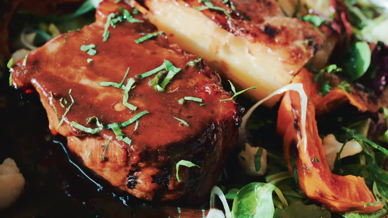 Close up of a gourmet meat dish with grilled vegetables, herbs, and rich sauce