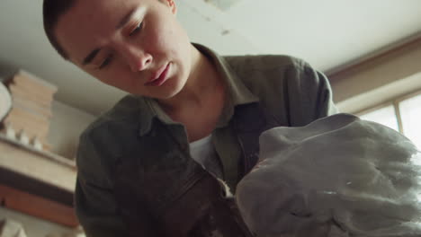 woman sculpting head out of clay