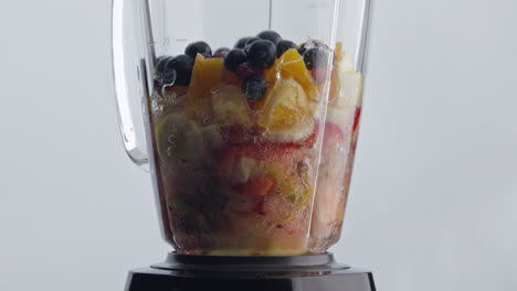 mezclador eléctrico mezclando frutas bayas con agua para cócteles naturales de cerca