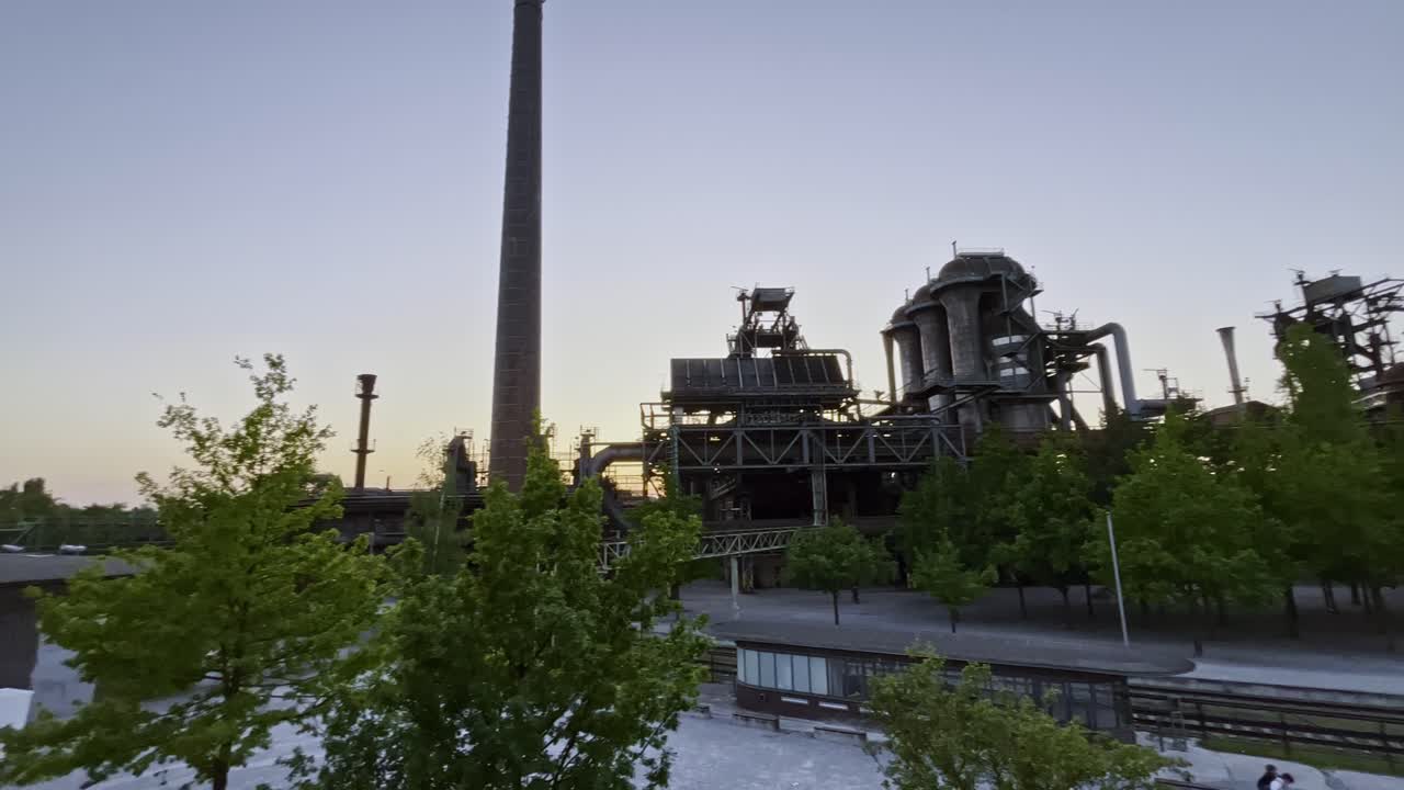 tomada amplia por la noche sobre el sitio de la fábrica en desuso landschaftspark duisburg en alemania al atardecer, tuberías y chimeneas