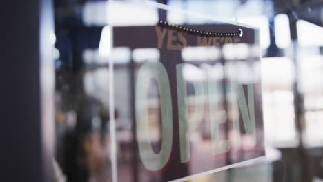 Nahaufnahme-Der-Hände-Einer-Cafébesitzerin,-Die-Das-Schild-„Geschlossen“-ändert,-Um-Es-Im-Fenster-Zu-öffnen