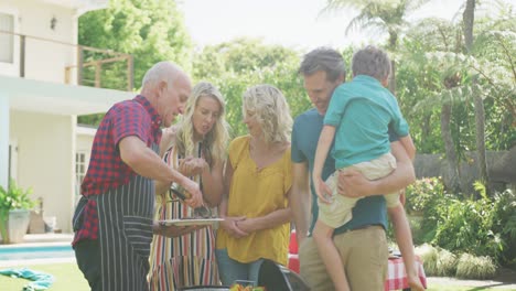 happy caucasian family having barbecue and eating in garden