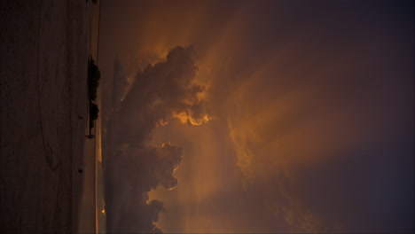 Toma-Panorámica-Vertical-De-Una-Puesta-De-Sol-Celestial-En-Cancún,-México,-Con-Rayos-De-Luz-Saliendo-De-Las-Nubes.