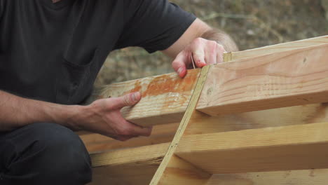 hombre sosteniendo tablones de madera en su lugar para el proyecto de mini rampa de patineta diy