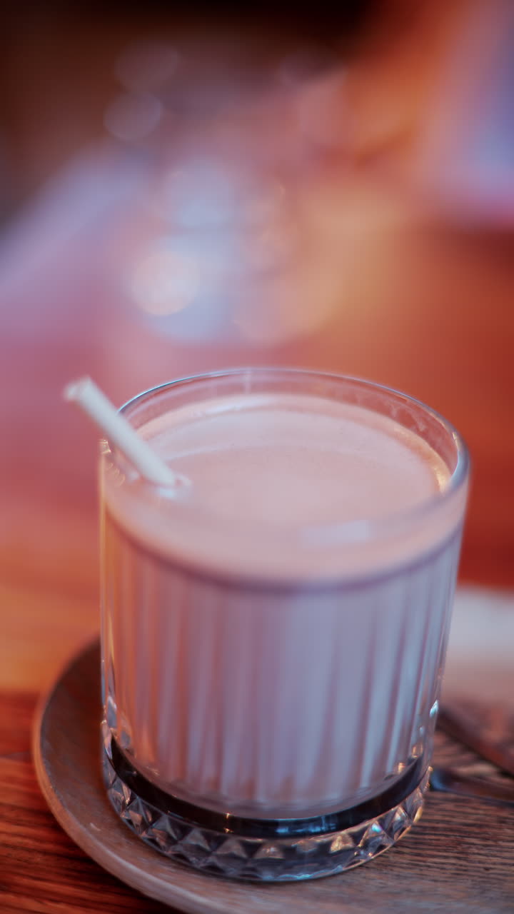 Primo piano di una cioccolata calda in un bicchiere con una cannuccia su un tavolo in un bar. Verticale