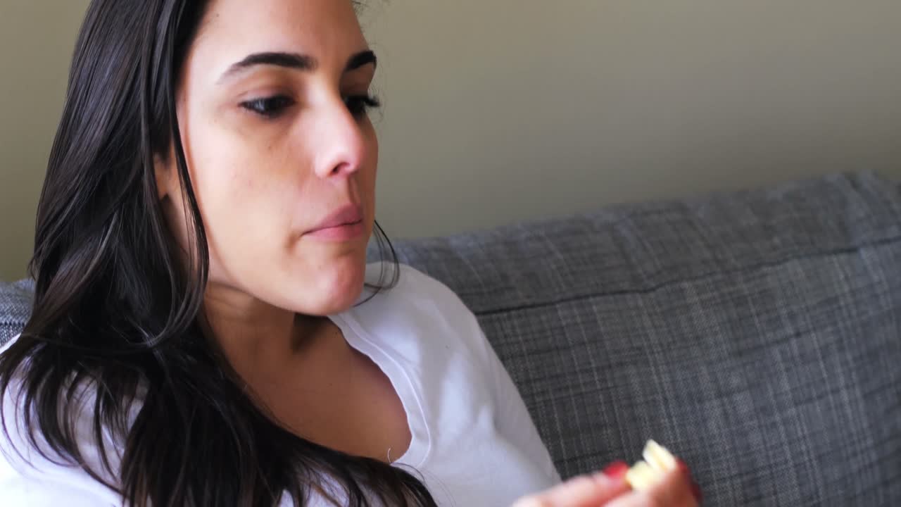 hermosa mujer comiendo palomitas de maíz en el sofá 4k