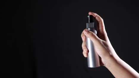 hand holding a silver spray bottle