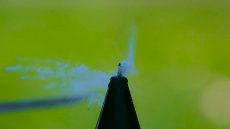 a candle flame being blown out by a flying playing card in slow motion during summer time while sun shines